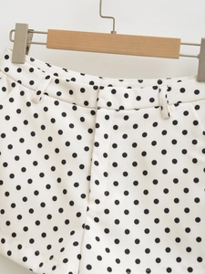 Detailed view of women's black and white polka dot shorts with waist and zipper details