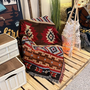 Macro shot of bohemian woven blanket with ethnic patterns and fringe detail in camping setup