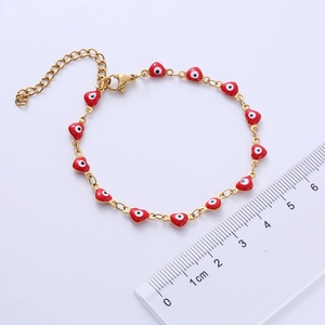Close-up of gold stainless steel heart bracelet with red enamel evil eye charms and ruler