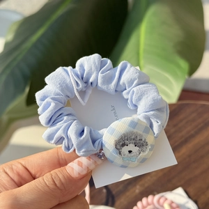 Detail of light blue scrunchie with embroidered poodle button and plaid pattern