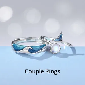 Ocean-themed silver couple rings with blue wave enamel and whale tail moonstone design