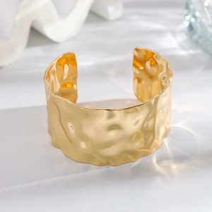 Exaggerated wide open bangle with golden hammered texture and ginkgo leaf inspired design