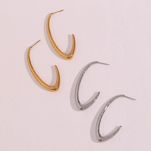 Macro detail of textured V-shaped hoop earrings in gold and silver stainless steel