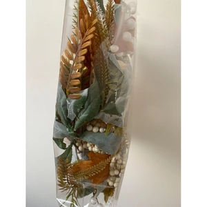Close-up of artificial autumn garland with white berries and maple leaves in plastic bag