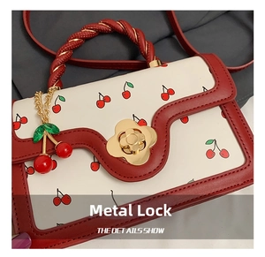 Detail of flower-shaped gold clasp and red twisted handle on cherry print handbag