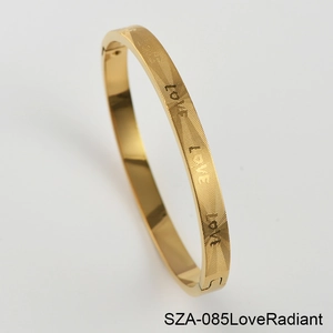 Detail of gold titanium steel bangle showing radiant texture and LOVE engraving with clasp