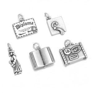 Macro shot of silver stainless steel graduation and travel charms with vintage finish