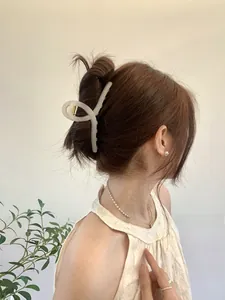 Detail of 13cm large cream white hair claw clip styled on a woman's hair in a low bun