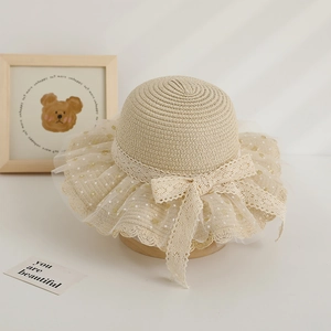 Détail d'un chapeau de paille pour fille avec nœud en dentelle et bord en tulle