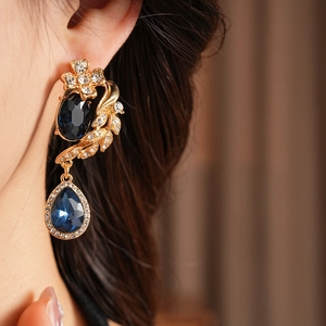 Détail de boucles d'oreilles vintage en or avec pierres bleues et cristaux micro-pave