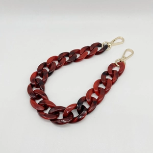 Close-up of tortoiseshell acrylic chain strap with gold lobster clasps on white background