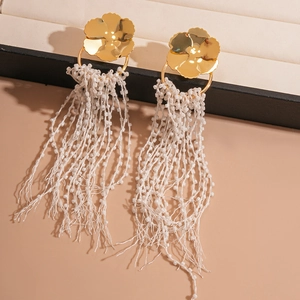 Dramatic gold floral earrings with long white glass bead tassels in a 45-degree angle view