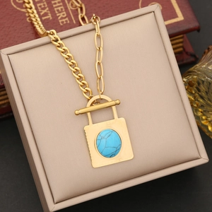 Detail of gold necklace with turquoise lock pendant and T-bar clasp on jewelry box