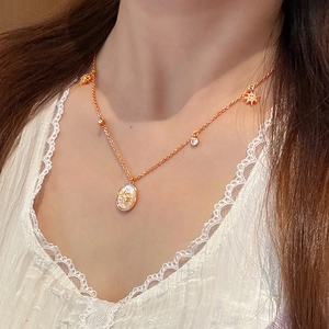 Détail d'un collier en nacre ovale plaqué or 18 carats avec pendentif étoile sur modèle