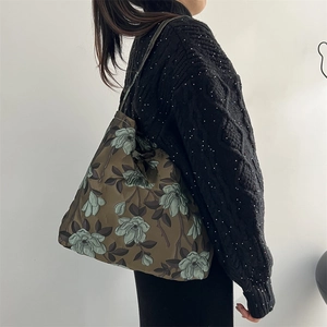 Dettaglio del motivo floreale vintage su borsa a spalla retrò verde scuro jacquard