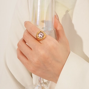 Dettaglio di un anello vintage dorato con grande gemma rosa tenendo un calice sottile