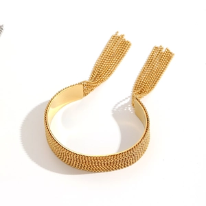 Detail view of a gold woven mesh bracelet featuring long fringe chain tassels on white background