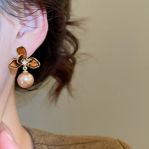 Close-up of vintage flower earrings with brown petals and champagne gold pearl pendant