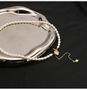 Detail shot of natural freshwater pearl necklace on wave metal tray with gold clasp