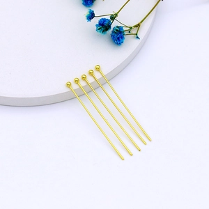 Macro shot of five 14k gold plated ball head pins for jewelry making on white base