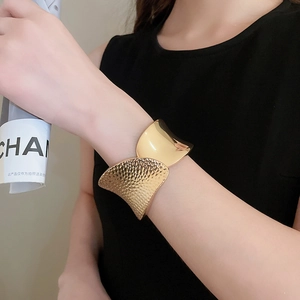 Close-up of golden wide open cuff with hammered texture and mirror polished finish