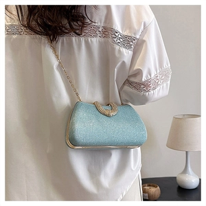 Detail of light blue glitter crossbody bag with gold heart clasp and chain strap