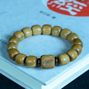 Gros plan d'un bracelet en perles de bois de santal avec perle carrée et gravures