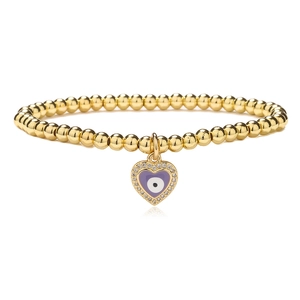 Close-up of golden beaded bracelet with purple enamel evil eye heart charm and pavé crystals