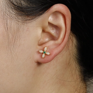 Golden flower earring with marquise white zircon petals and green stone center on ear