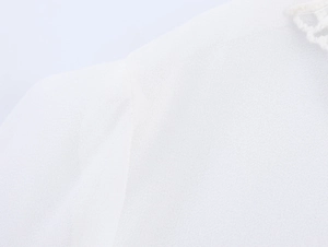 Macro detail showing the white chiffon fabric texture and delicate lace neckline trim