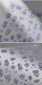 Macro shot of 3D embossed blue butterfly and tulip nail stickers with laser silver edges