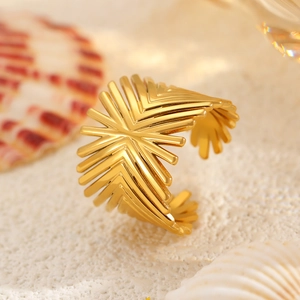 Macro shot of gold geometric sunburst ring on sand background with beach holiday vibe
