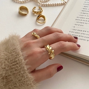 Close-up of vintage gold chunky heart rings and braided bands on model's hand