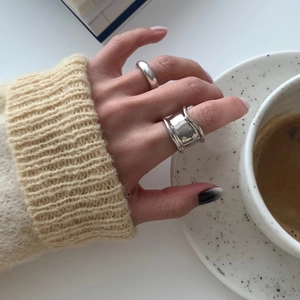 Detail of minimalist 925 sterling silver geometric wide ring on a model in knitwear