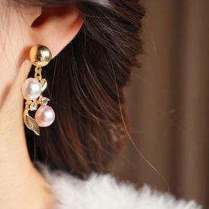 Détail de boucles d'oreilles vintage en or avec perles roses et blanches sur un mannequin