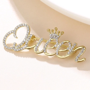 Elegant gold Queen crown brooch featuring shimmering rhinestones on a textured background