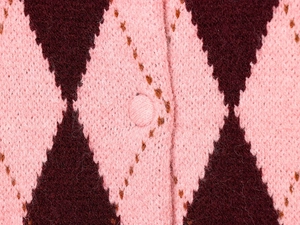 Macro view of pink argyle knit cardigan with high-quality plush texture and fabric button