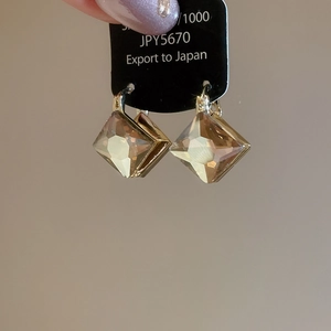 Detail shot of vintage rhombus earrings with amber crystal and gold plating