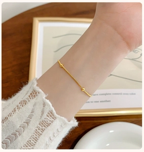 Elegant gold snake chain bracelet with small beads worn on wrist in a refined setting