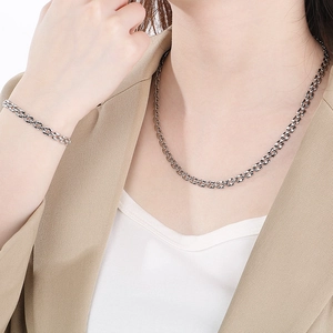 Close-up of elegant silver hollow square pendant necklace and bracelet set on a model
