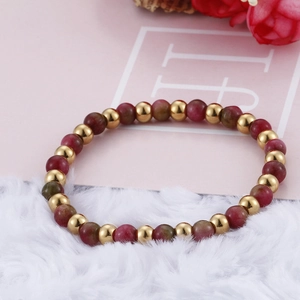 Minimalist gold-plated beaded bracelet with red garnet stones on soft plush background