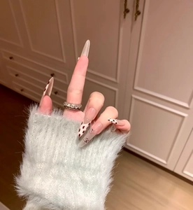 Détail de longs faux ongles amande avec motif léopard, strass et nœud papillon