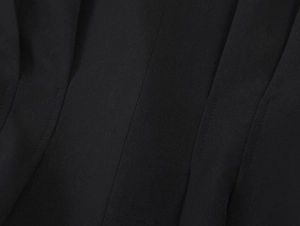 Close-up of black blazer fabric showing detailed weave texture and precise stitching