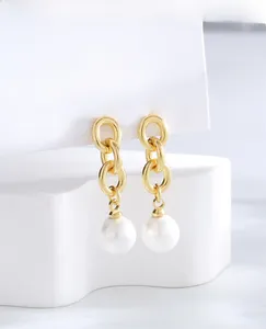 Detailed macro of gold plated drop earrings featuring interlocking rings and white pearls