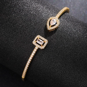 Macro shot of gold open bangle featuring teardrop and rectangular crystal settings