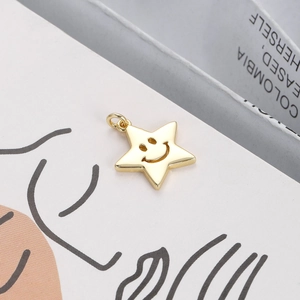 Detailed close-up of a 18K gold-plated star pendant with an engraved smiley face icon