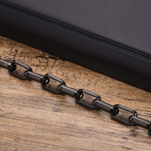 Detailed close-up of a glossy black stainless steel square link bracelet on wood