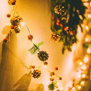Christmas garland string lights with red berries, pine cones and warm LED glow