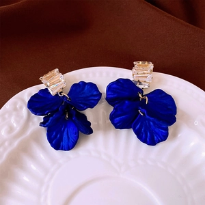 Close-up of royal blue matte flower earrings with gold-plated baguette-cut crystals