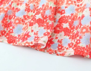 Dettaglio del tessuto in chiffon floreale rosso e azzurro con cucitura dell'orlo